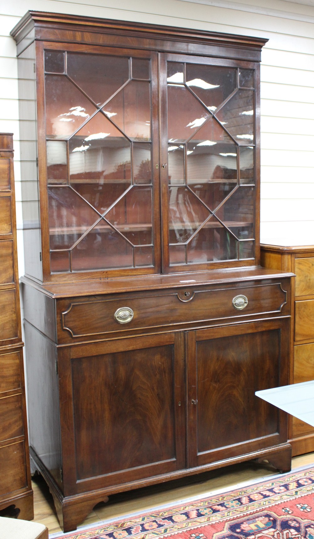 A George III style mahogany bookcase, with two astragal glazed doors over a fall front drawer and panelled doors, W.127cm D.62cm H.226c